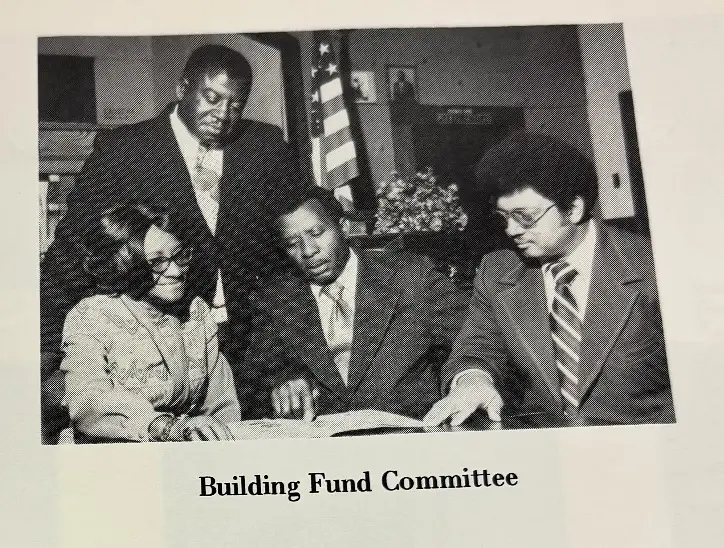 Archival photo captioned Building Fund Committee showing four church members reviewing documents at a table
